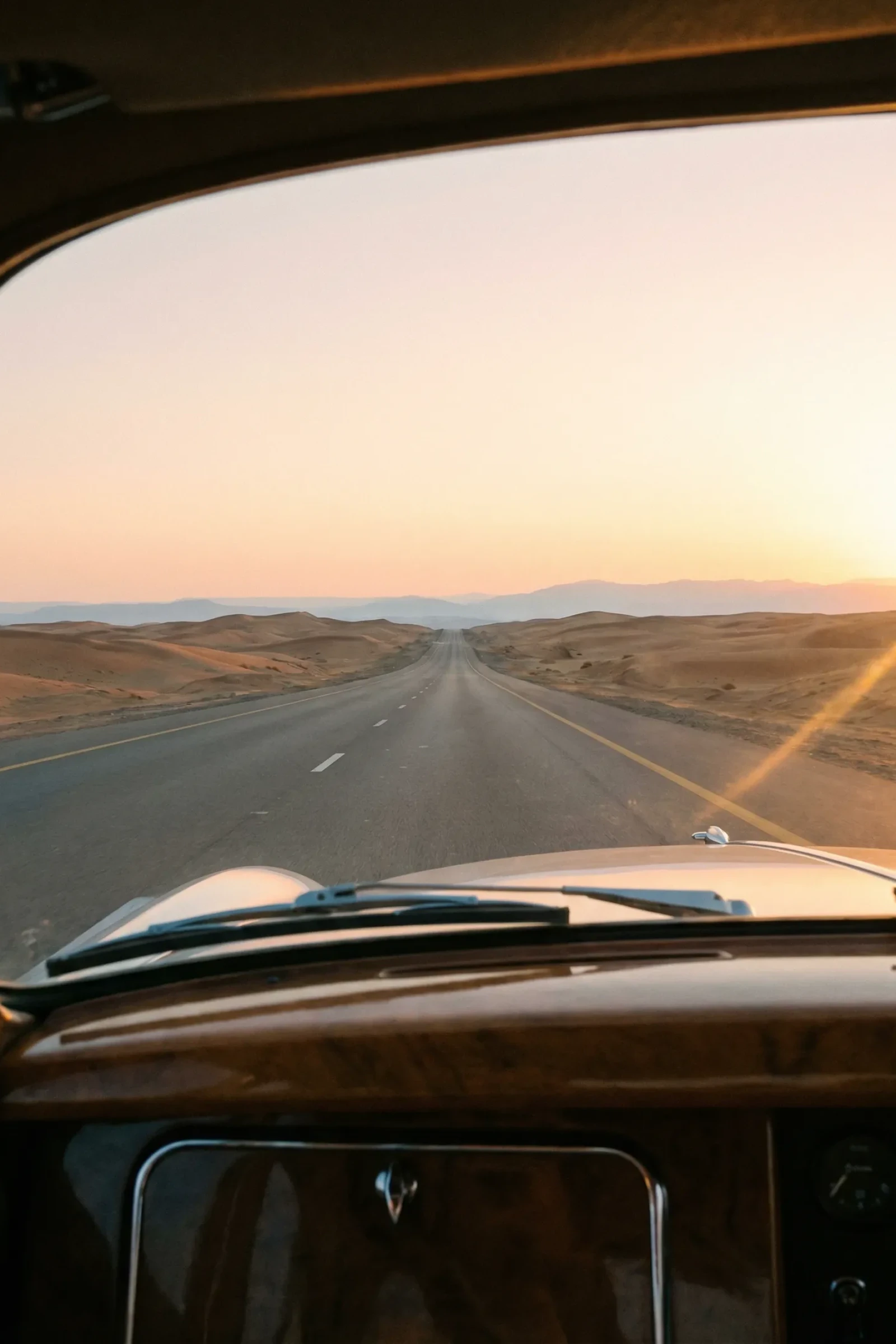 An empty desert road stretching toward the horizon in the UAE